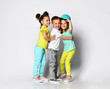 © FAB.1 - Studio portrait of children on a light background: full body shot of three children in bright clothes, two girls and one boy. Triplets, brother and sisters. hugging on camera.