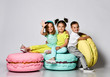 © FAB.1 - Three friends of triplets - two girls and a boy in bright clothes have fun at the birthday party fun room decoration candy macarons