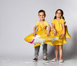 © FAB.1 - Positive young children hold a balloon in the shape of a yellow shark fish, celebrate the holiday, smiling widely, stand on a light background, are in a good mood