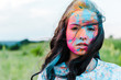 attractive young woman with colorful holi paints looking at camera