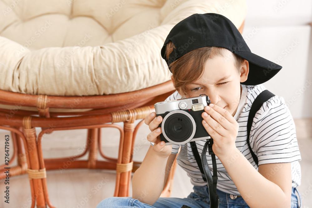 Cute little photographer with professional camera at home