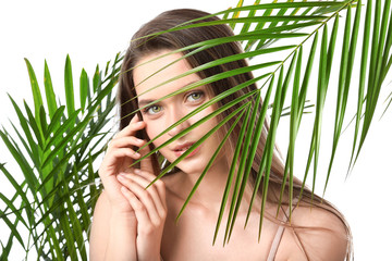 Wall Mural - Beautiful young woman with tropical leaves on white background