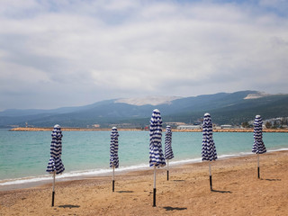 Folded umbrellas on the sandy beach of Mediterranean Sea