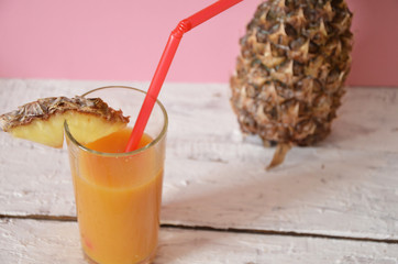 Pineapple cocktail or juice in glass bottles with straws with ice and pineapples on a blue or pink background