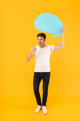 Poster - Photo of positive man in basic t-shirt showing thumb up and holding blank thought bubble