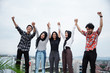 © Odua Images - five young people hanging out and raise hand together on the building rooftop
