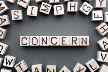 Fototapete - the word concern wooden cubes with burnt letters, gray background top view, scattered cubes around random letters