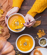 © Diana Vyshniakova - Woman's hands holding table sppoon near the bowl of delecious homemade pumpkin soup with cream on the wooden table top view