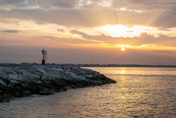 Lighthouse at sunset on Italian sea coast.