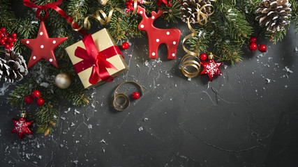 Aufkleber - Festive Christmas bright dark black background with beautiful texture and Golden gift box, red ribbon, fir branches, cones, Christmas tree toys stars, red deer, top view, copy space.