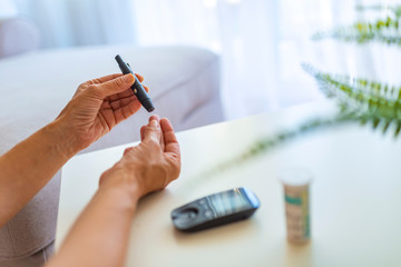 Wall Mural - Diabetes doing blood glucose measurement. Woman using lancet and glucometer. Woman doing test with blood glucose monitor. Use as Medicine, diabetes, glycemia, health care and people concept.