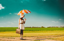 Photo Of Beautiful Young Woman With Suitcase And Umbrella On The Road Near Field Background