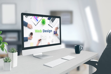 web design text on computer display. concept of web design studio. work desk, office interior.