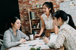 © PR Image Factory - smiling female boss addressing meeting around boardroom table. girls workers looking at pensive colleague and waiting for her to give opinion. happy women coworkers staring at thoughtful lady.
