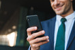 © Drobot Dean - Croppes image of smiling positive young business man using mobile phone.