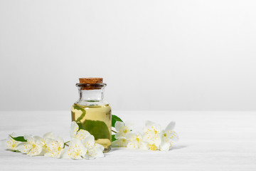 Wall Mural - flowers of philadelphus somewhere called jasmine or mock orange and a bottle of oil on a white wooden table