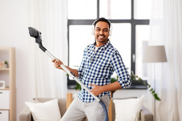 Sticker - household and cleaning concept - indian man in headphones with vacuum cleaner having fun at home