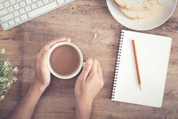 Wall Mural - top view of business hand on desk have coffee, toast, notebook blank and pencil on
