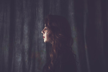 sad girl is standing on a black background with a offended face. emotion disorder