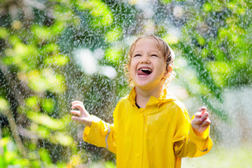 Wall Mural - Child playing in the rain. Kid with umbrella.