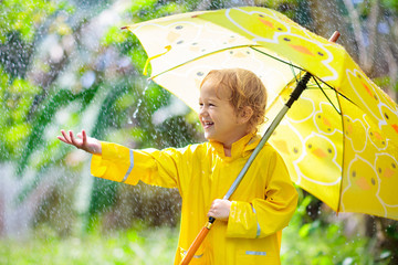 Wall Mural - Child playing in the rain. Kid with umbrella.