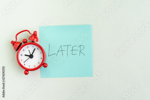 Fotomural Procrastination, postpone or laziness concept, red alarm clock on sticky note wi