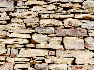 Fragment of stone masonry of light colored stone with natural light, close-up