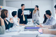 © Yingyaipumi - Businesswoman presenting to colleagues at a meeting.Successful team leader and business owner leading informal in-house business meeting. Businessman working on laptop in foreground.