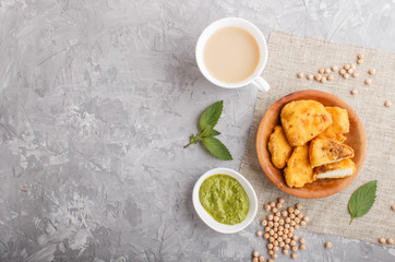 Wall Mural - traditional indian food paneer pakora in wooden  plate with mint chutney on a gray concrete background. top view.