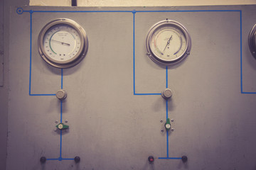 2 pressure gauges mounted on the wooden cabinet, along with the direction signs of the circuit