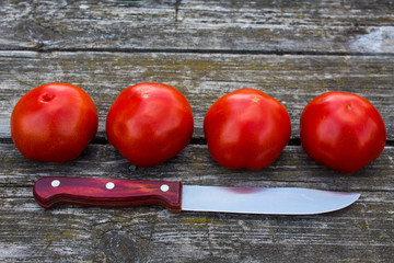 Four ripe red tomatoes on an old wooden table