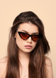 sunglasses girl, close up studio shot of beautiful fashion young woman model with long hair looking at camera . while posing against clean cream blank copy space wall for your content
