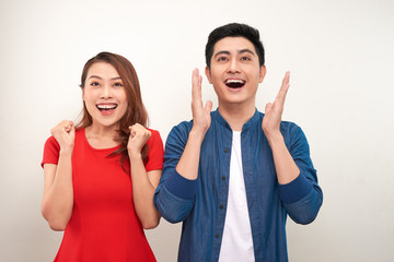 Young asian couple in love over isolated background celebrating surprised and amazed for success with arms raised and open eyes