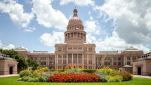 Texas State Capitol In Austin, Texas On A Sunny Summer Day With Colorful Flowers In The Front Yard