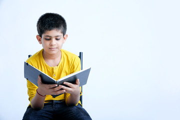 Young indian cute child reading a book