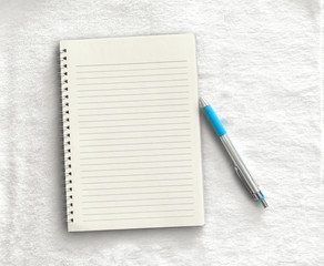 Notebook,pen on a white cloth background. top view copy space