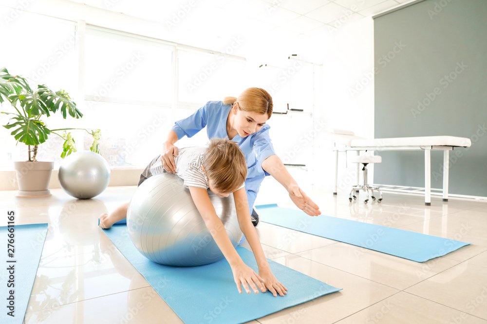 Physiotherapist working with little boy in rehabilitation center