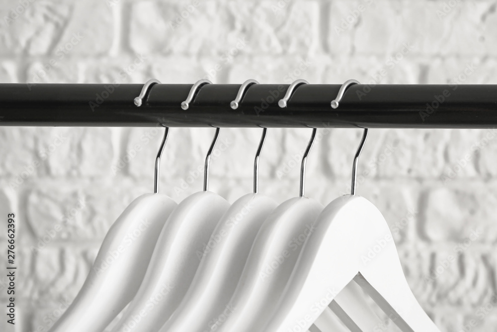 Rack with clothes hangers on white background, closeup