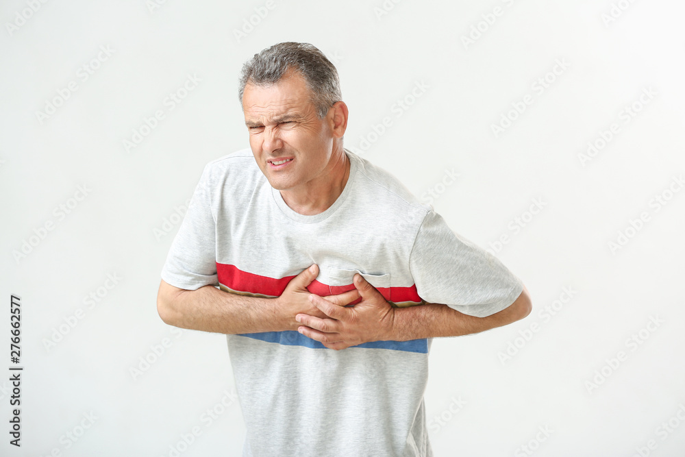 Mature man suffering from heart attack on white background