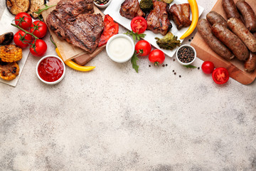 Tasty grilled meat with sausages and vegetables on light background