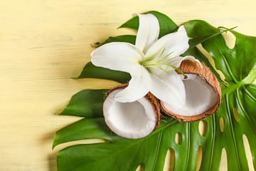 Tropical leaf with coconut and flower on wooden background