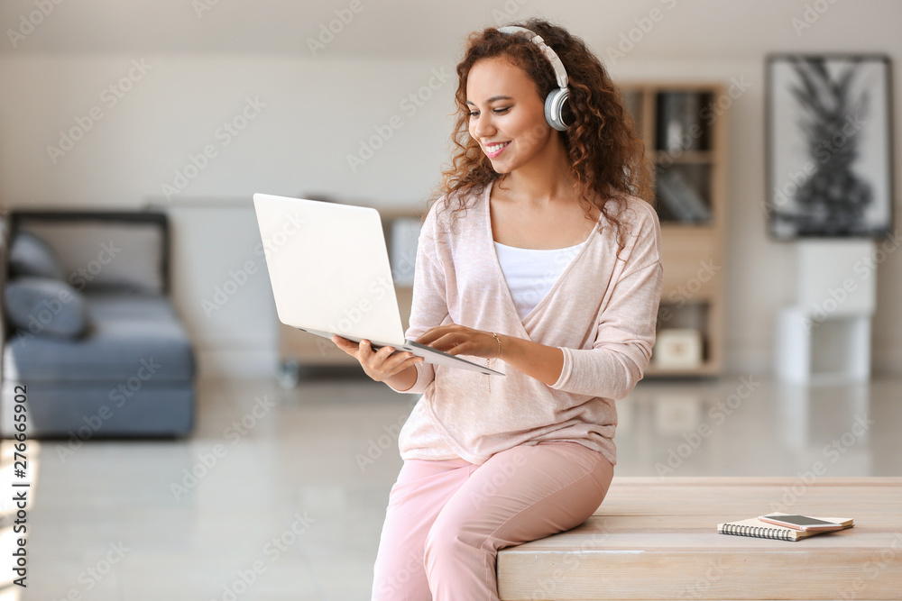 Young African-American student listening to music while preparing for exam
