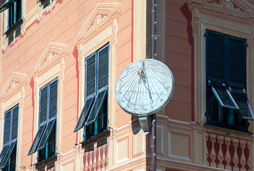 Wall Mural - A circle sundial on the corner of an old building in the historical centre of Rapallo, Genoa, Liguria, Italy