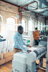 Wall Mural - Dark-skinned man working in printing office waiting for the poster