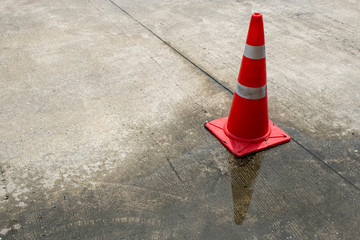 Close-up of spilled water Logged on the road with cone. Wet floor from rainy splash or pipelines water leakage on the road. Danger accident urban city  from slippery road hazard concept.