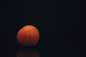 Poster - Fresh tomato on a black glass table and dark background.