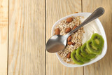 Fototapeta  - Greek white yogurt with kiwi almonds and oatmeal on a natural wooden table. breakfast. top view