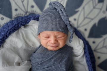 Newborn baby boy wrapped in gray fabric