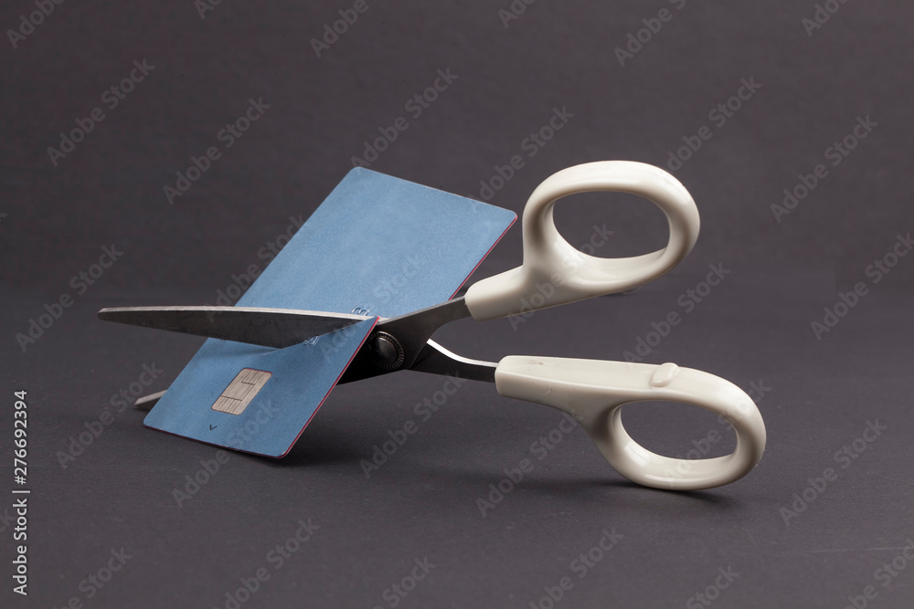 A pair of scissors cutting a credit card in half over a white ...