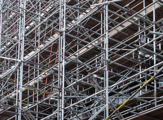 a dense network of metal scaffolding poles supporting work platforms on a construction site